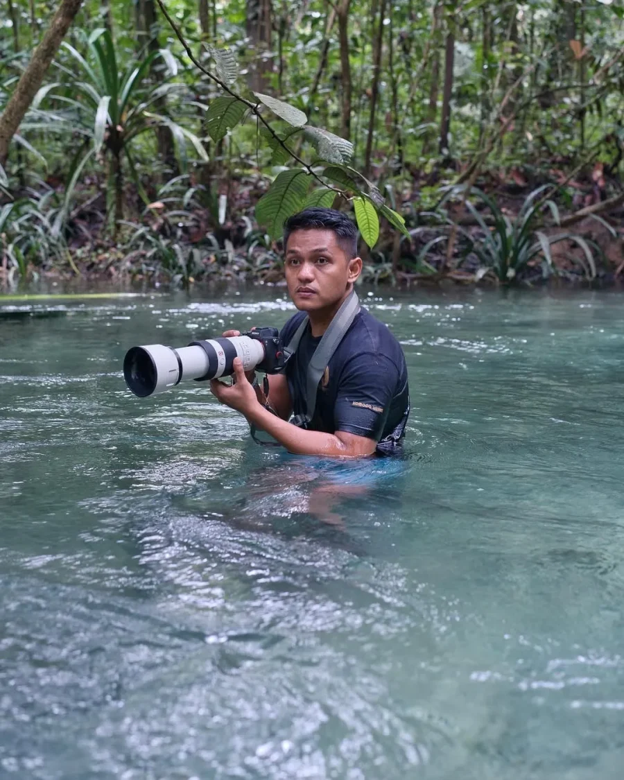 Agung Afif photographing in a river with a telephoto lens