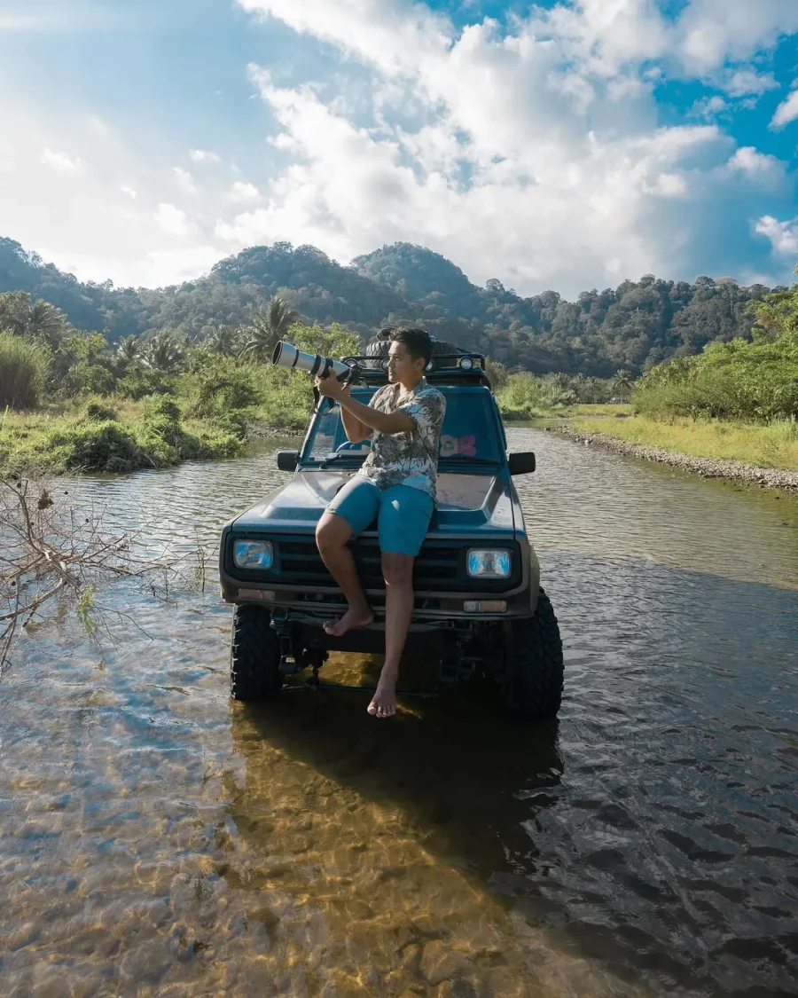 Agung Afif filming from the bonnet of an off-road vehicle in a river